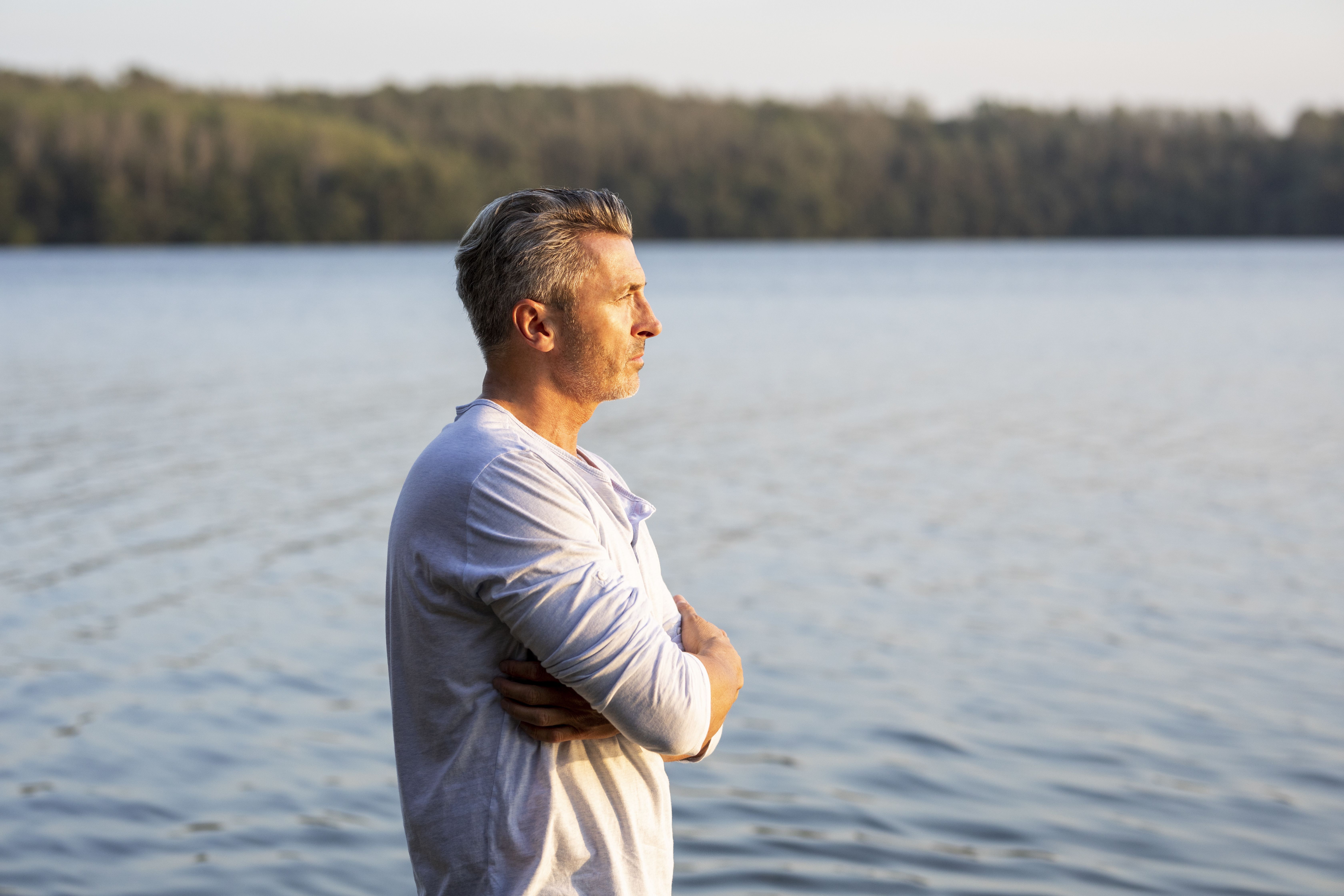 Muž kolem padesátky hledící s klidem na jezero, což ilustruje nový začátek a hledání vážného vztahu po rozvodu.